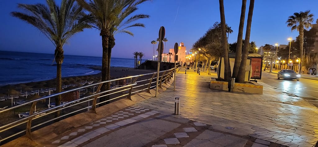 Well-illuminated seaside promenade at night with pedestrians