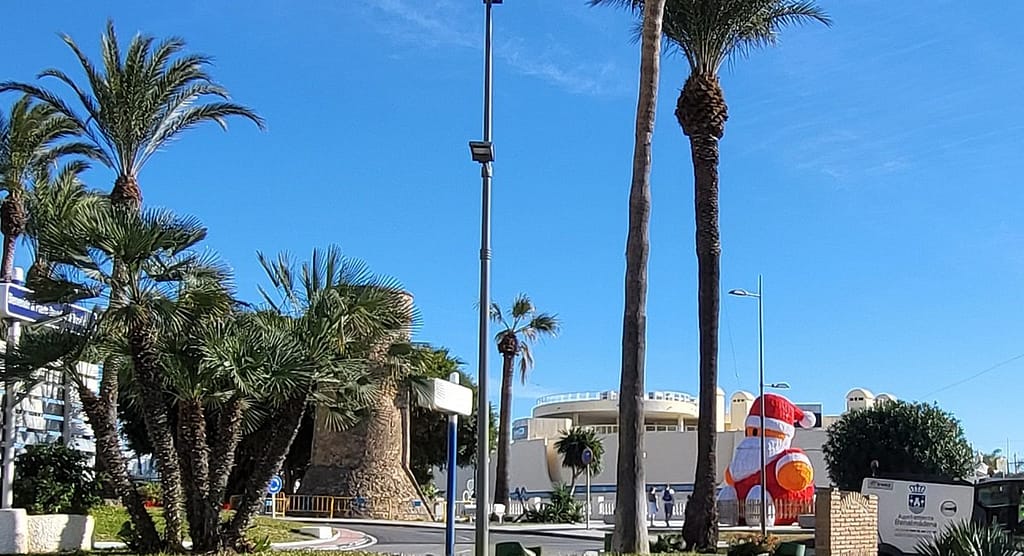 Near the port, visitors stop by a large Santa Claus to enjoy summer-like Benalmadena weather in mid-December