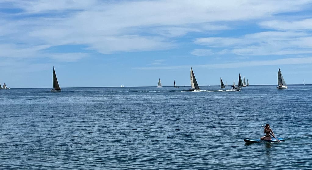 The sea with yachts in the distance and a kayaker closer to the beach