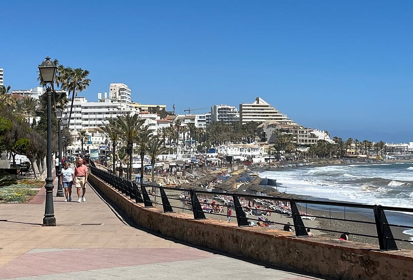 A seaside promenade runs along the beach in central Benalmadena with hotels in the distance 