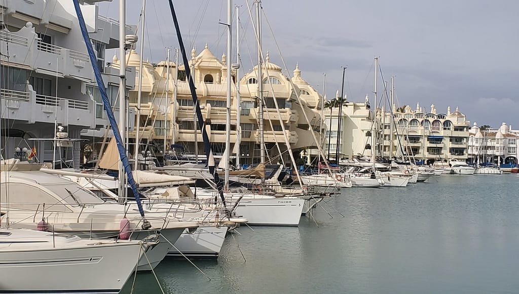 White yachts moored along residential buildings in Benalmadena's port 